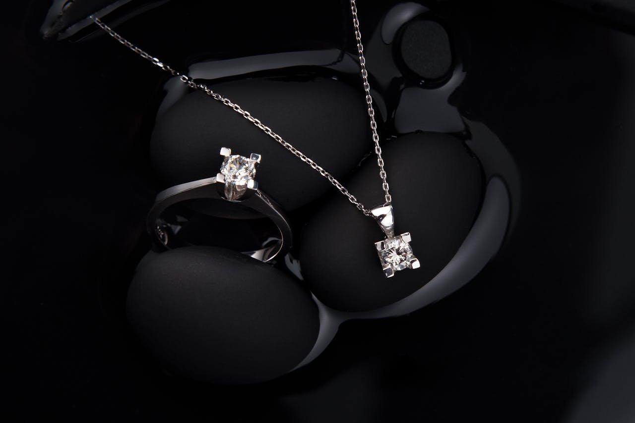 Luxurious silver diamond ring and pendant necklace on a black background, showcasing elegance and sophistication.